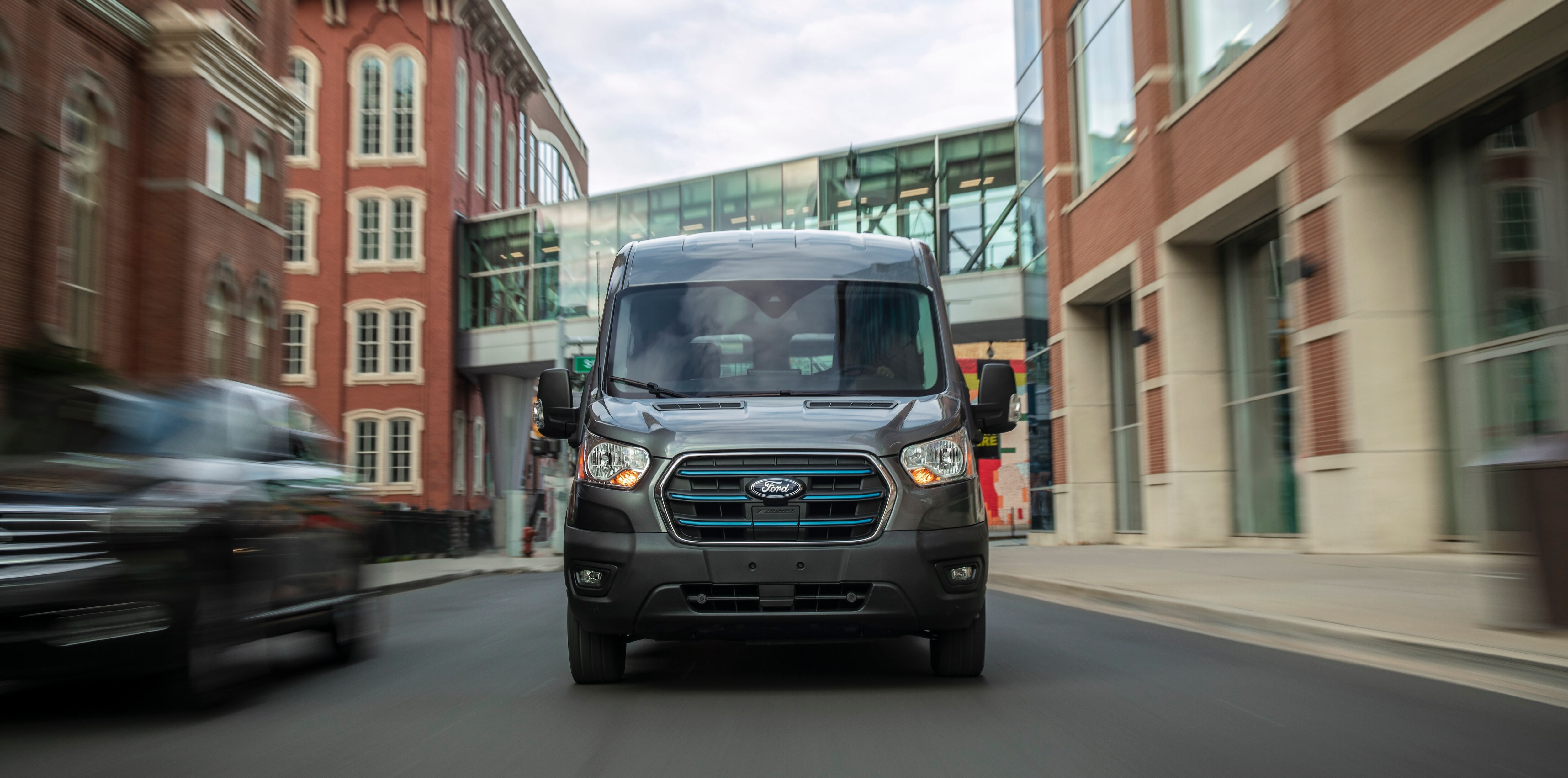  A silver E-Transit™ van being driven down a city street